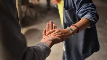 Image of two people reaching out and grabbing each other's hand.