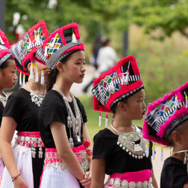 Young women standing in line wearing colorful cultural dance costumes.