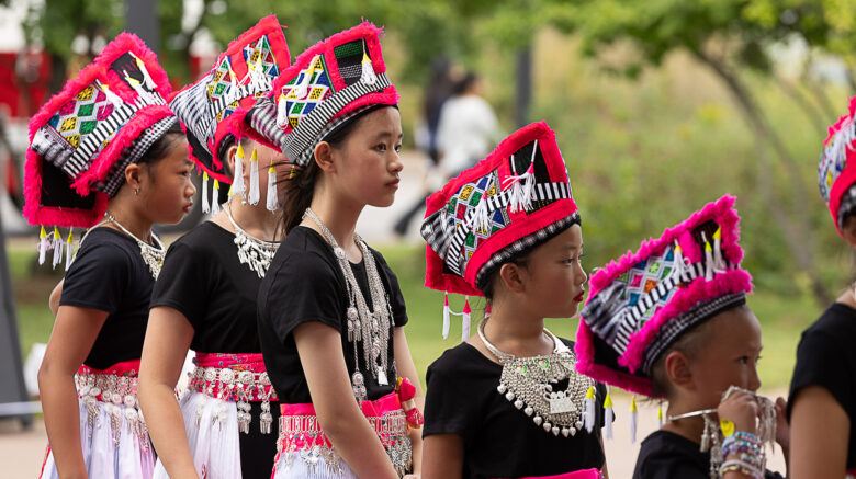 Young women standing in line wearing colorful cultural dance costumes.