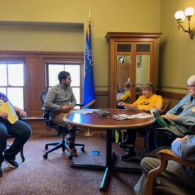 Image of five people seated around a table in an office.