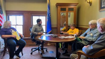 Image of five people seated around a table in an office.