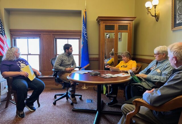 Image of five people seated around a table in an office.