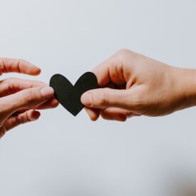 Image of two hands holding a paper heart.