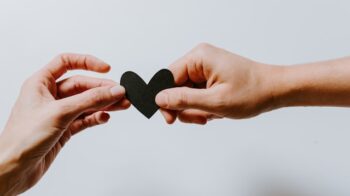 Image of two hands holding a paper heart.