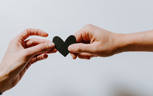 Image of two hands holding a paper heart.