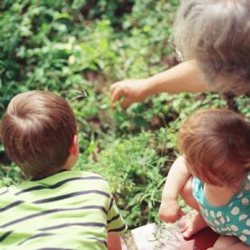 Grandparent with children in a garden.