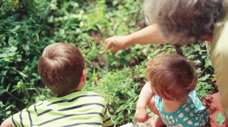 Grandparent with children in a garden.
