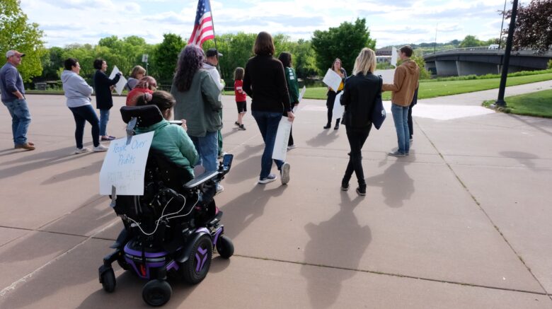 Group of people march with signs and American flag.