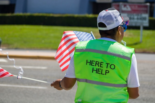 Person wearing a vest that says, "Here to help"